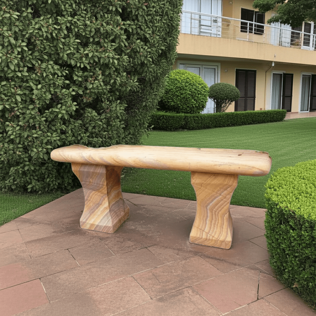 Natural rainbow sandstone garden bench placed on a paved patio with a modern villa and lush greenery in the background.