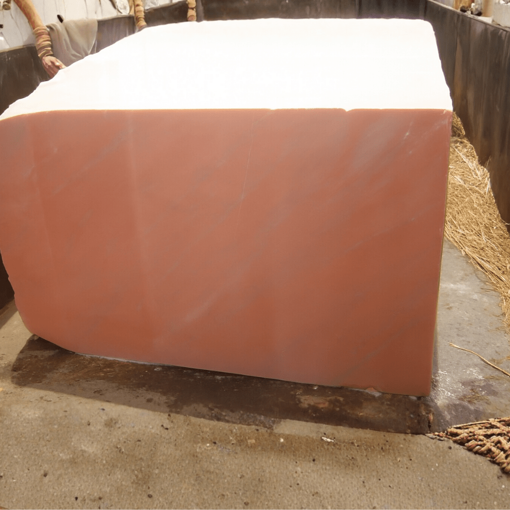 Stacked pink marble blocks in a factory yard ready for cutting and polishing.