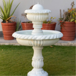 A classic two-tier white marble garden fountain featuring hand-carved fluted details and a rope-edge bowl, installed on a green outdoor lawn.